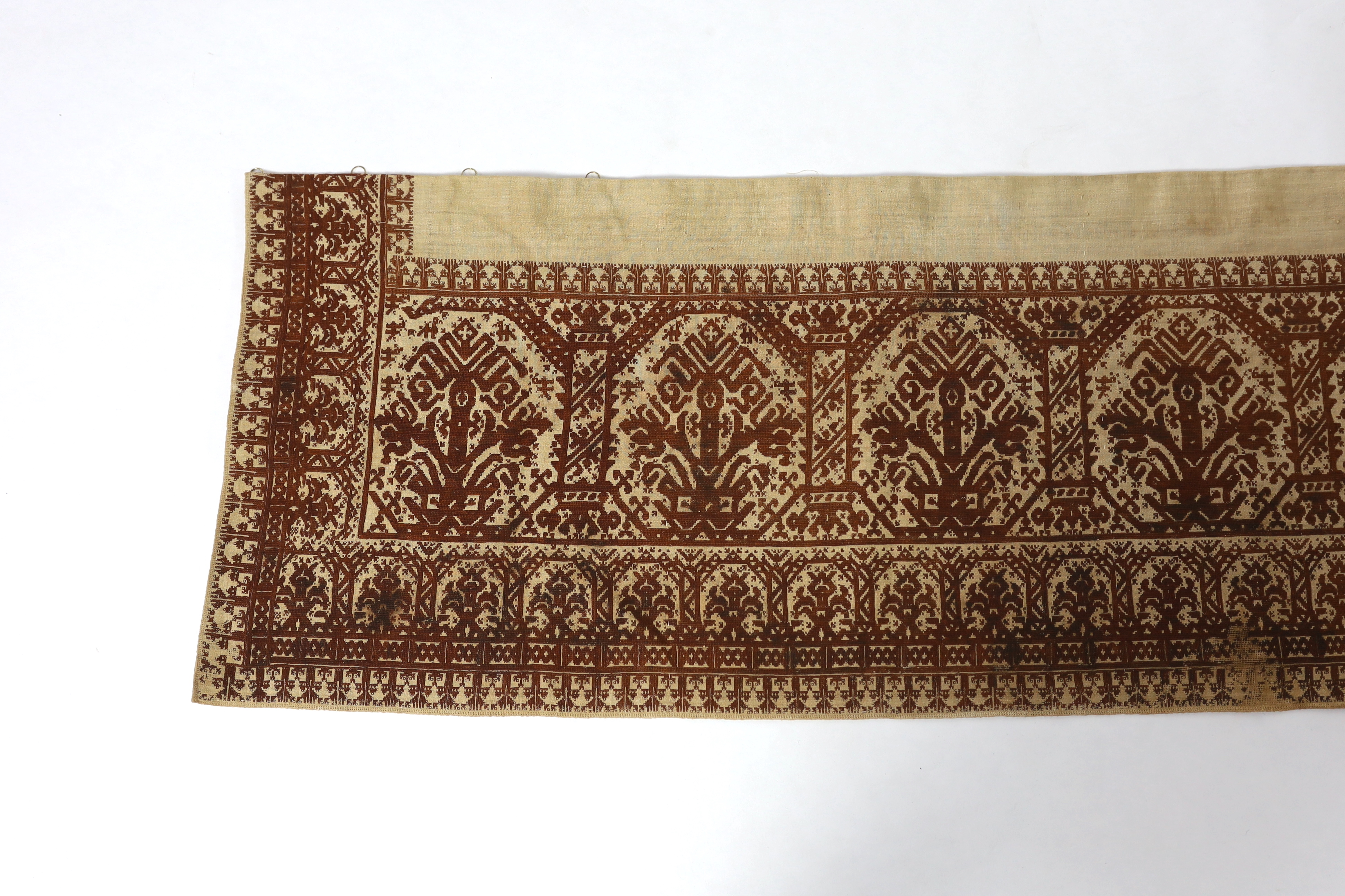 An early 19th century long Greek Islands cross stitch pelmet (hanging), embroidered on coarse linen with brown silk, using cross stitch, designed in horizontal rows of similar symbols, the lower row being a smaller size,